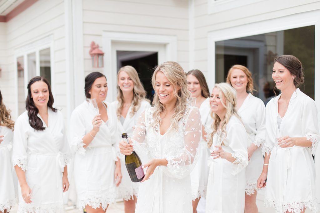 popping champagne all white bridesmaids robes at southern wedding by Costola Photography
