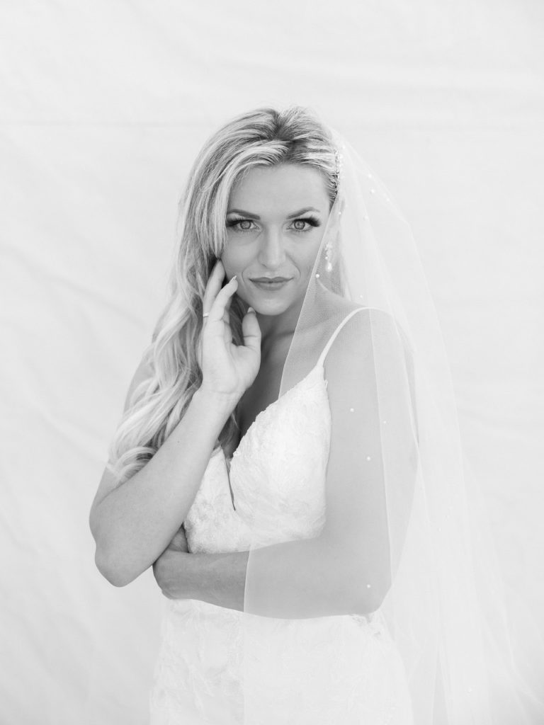 A close-up portrait of a bride with hands on face to look more flattering